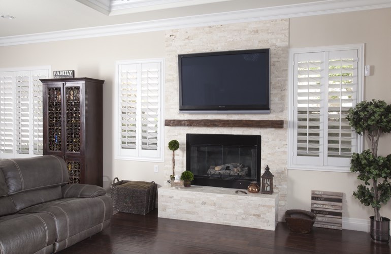 White plantation shutters in a Denver living room with dark hardwood floors.